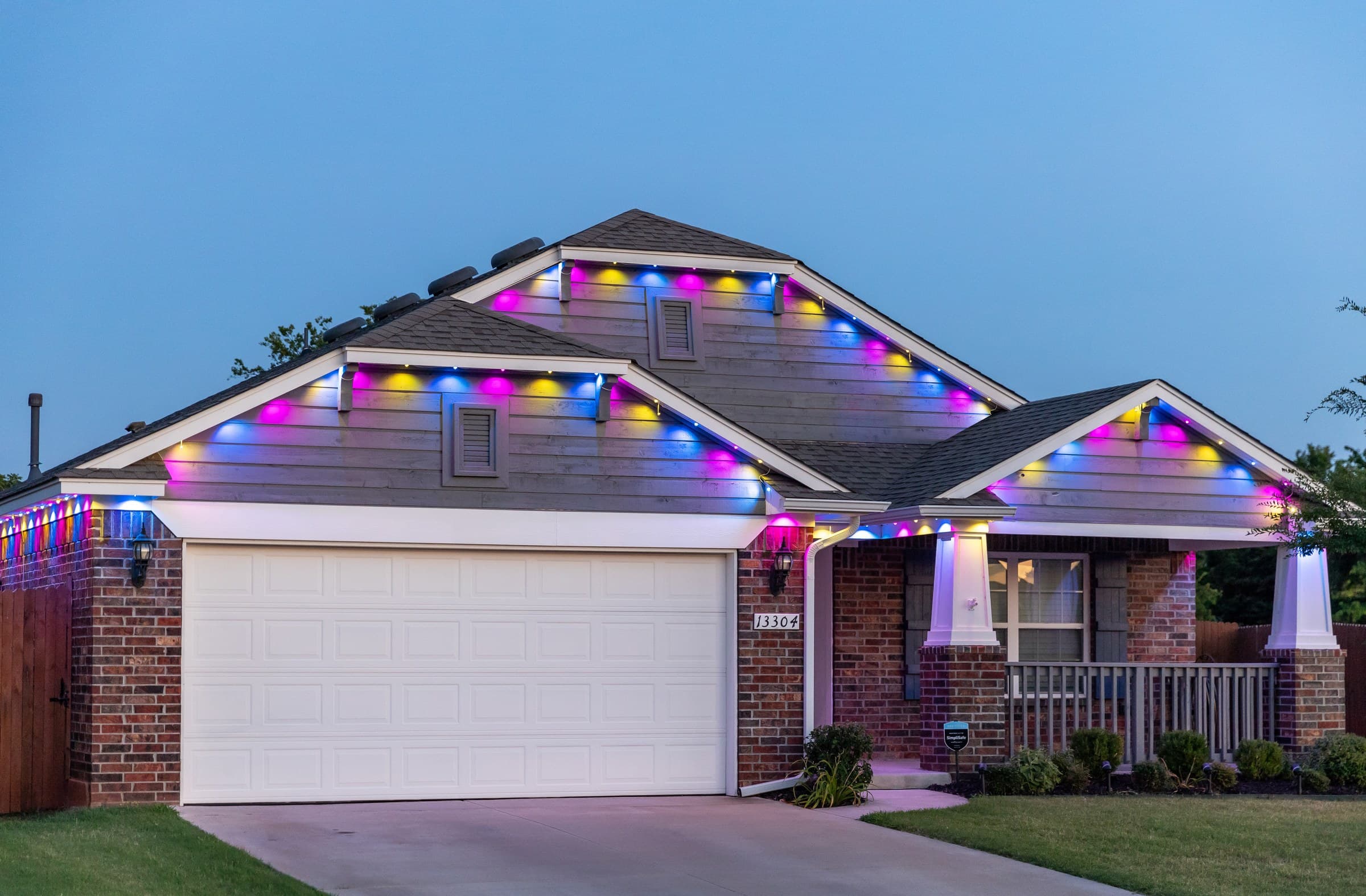 A brick ranch at dusk running an alternating multi-color scene along the eave and gable lines