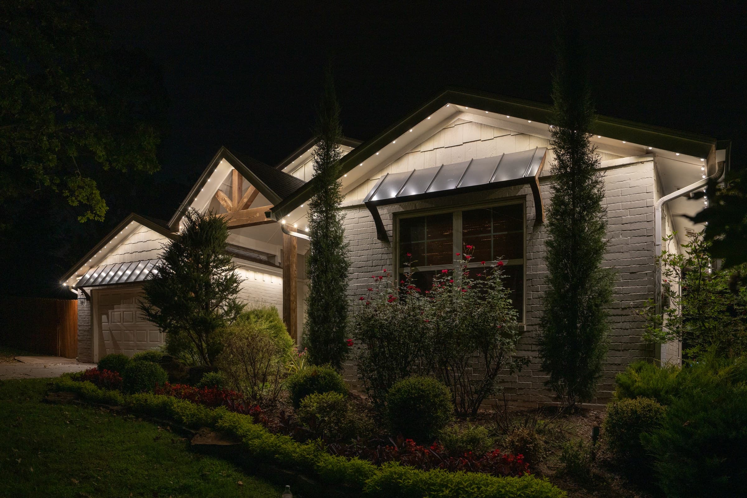 Close view of a white-painted brick elevation washed in warm white light from the eave line